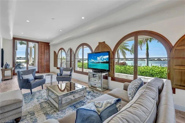a living room with furniture a fireplace and floor to ceiling windows