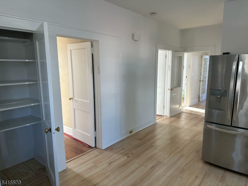 186 Main Avenue Passaic, NJ 07055 - Photo 4 of 13 a view of a refrigerator in kitchen and an empty room with wooden floor windows