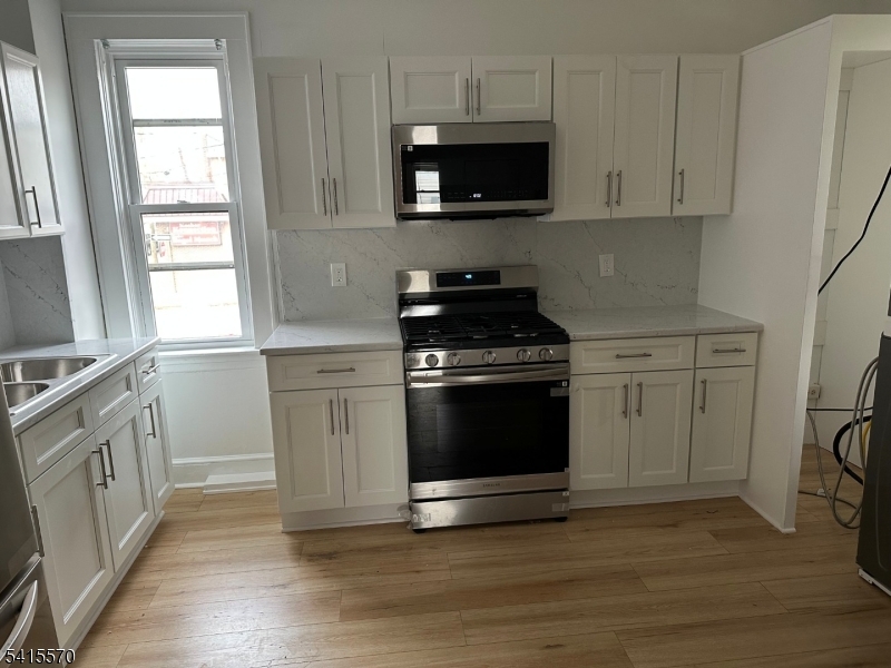 186 Main Avenue Passaic, NJ 07055 - Photo 6 of 13 a kitchen with stainless steel appliances a stove a microwave and sink