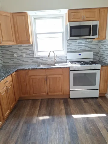 a kitchen with granite countertop a stove a sink and a microwave