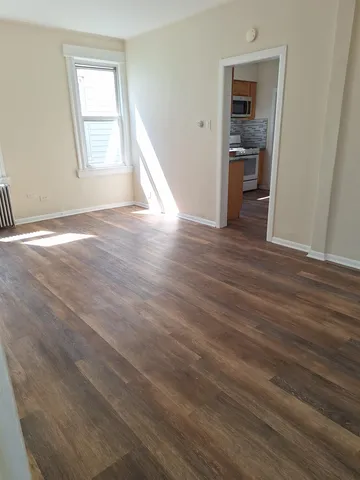 an empty room with wooden floor and a window