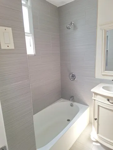 a bathroom with a tub shower and vanity