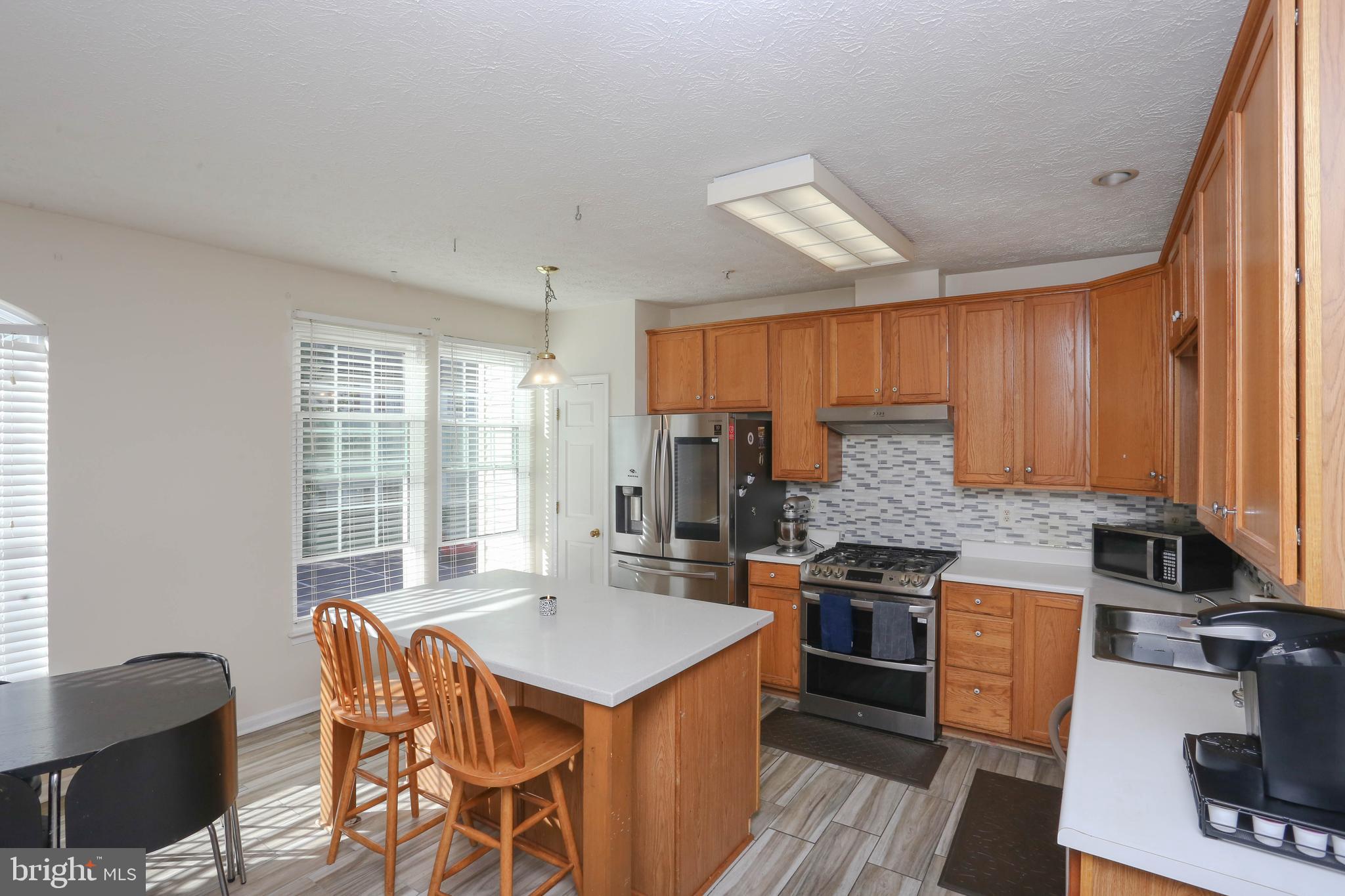 1734 Sea Pine Circle, Unit 136 Severn, MD 21144 - Photo 13 of 32 a kitchen with stainless steel appliances granite countertop a stove top oven a sink dishwasher a dining table and chairs with wooden floor