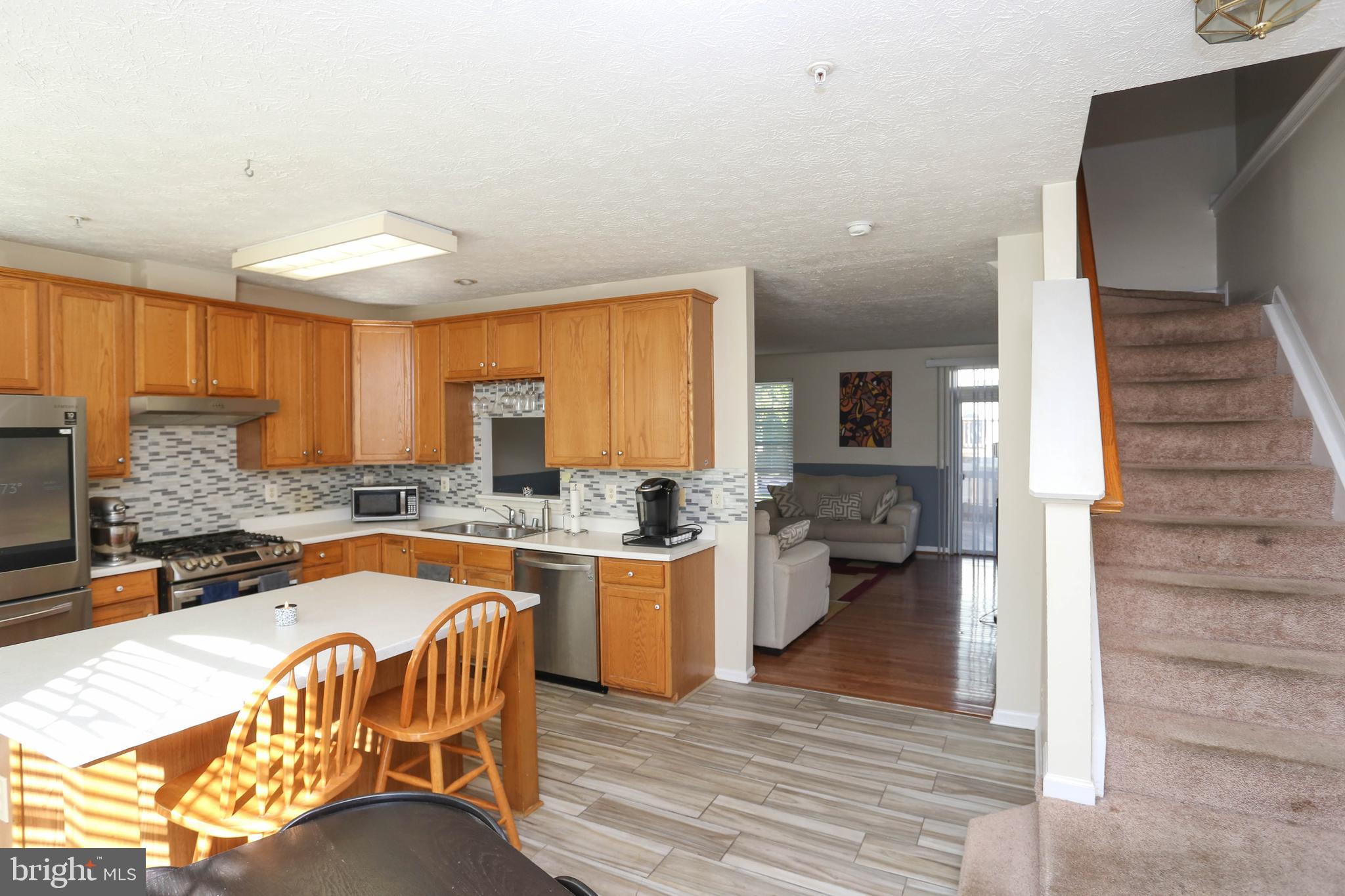 1734 Sea Pine Circle, Unit 136 Severn, MD 21144 - Photo 14 of 32 a kitchen with a table chairs stove and cabinets