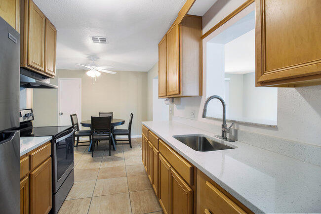 2879 Lancaster Road Melbourne, FL 32935 - Photo 6 of 28 a kitchen with kitchen island granite countertop a sink a counter top space appliances and cabinets