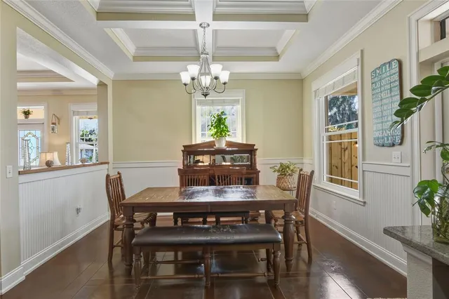 a view of a dining room with furniture a chandelier and kitchen view