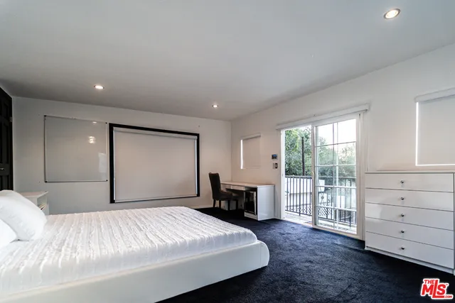 a bedroom with a large bed and wooden floor