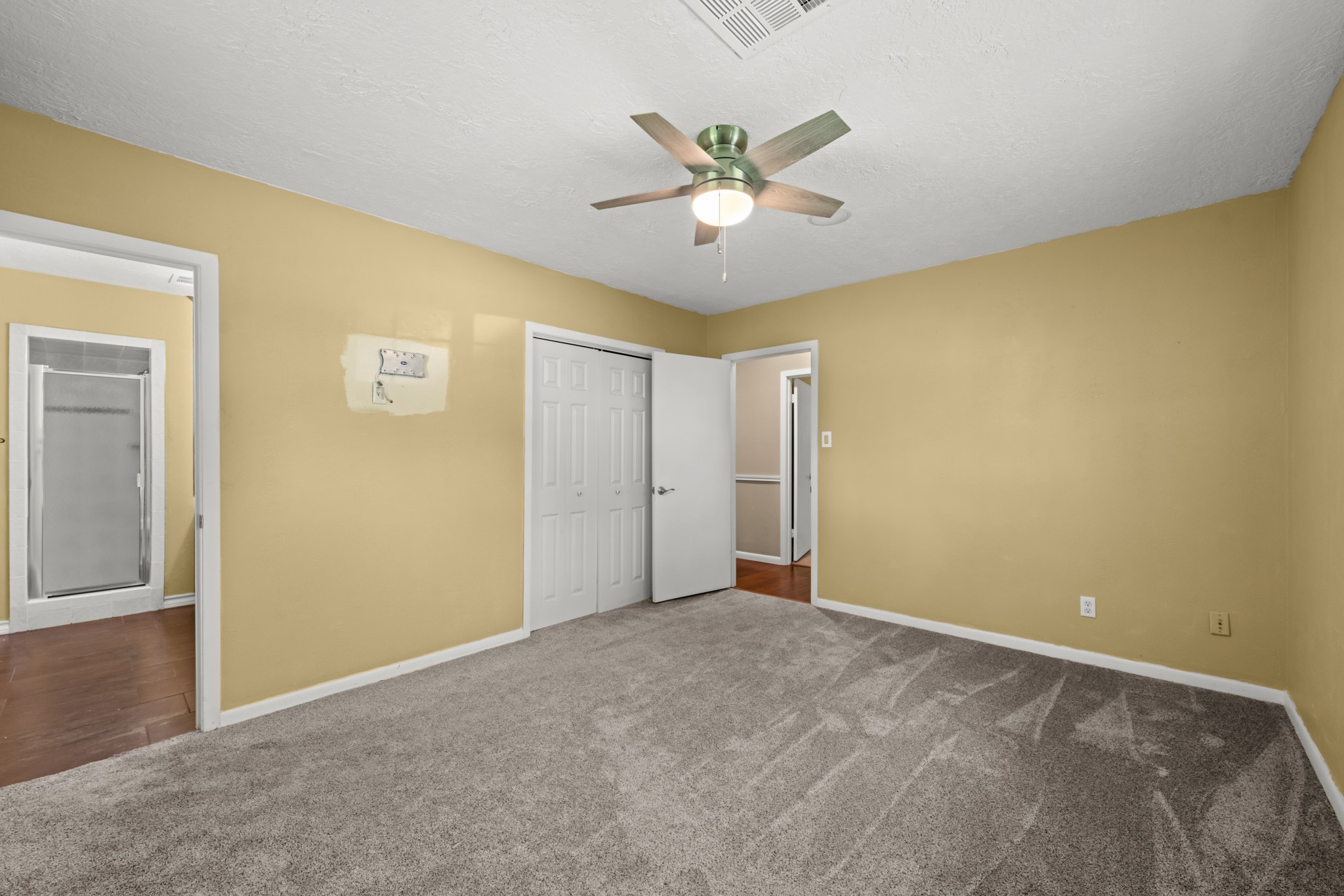 616 Cannan Drive Angleton, TX 77515 - Photo 20 of 49 This spacious primary suite offers plush carpeting, a ceiling fan, and ample room for a full bedroom furniture arrangement. The private en-suite bath and generous closet storage enhance comfort and functionality, creating a relaxing retreat at the end of the day.
