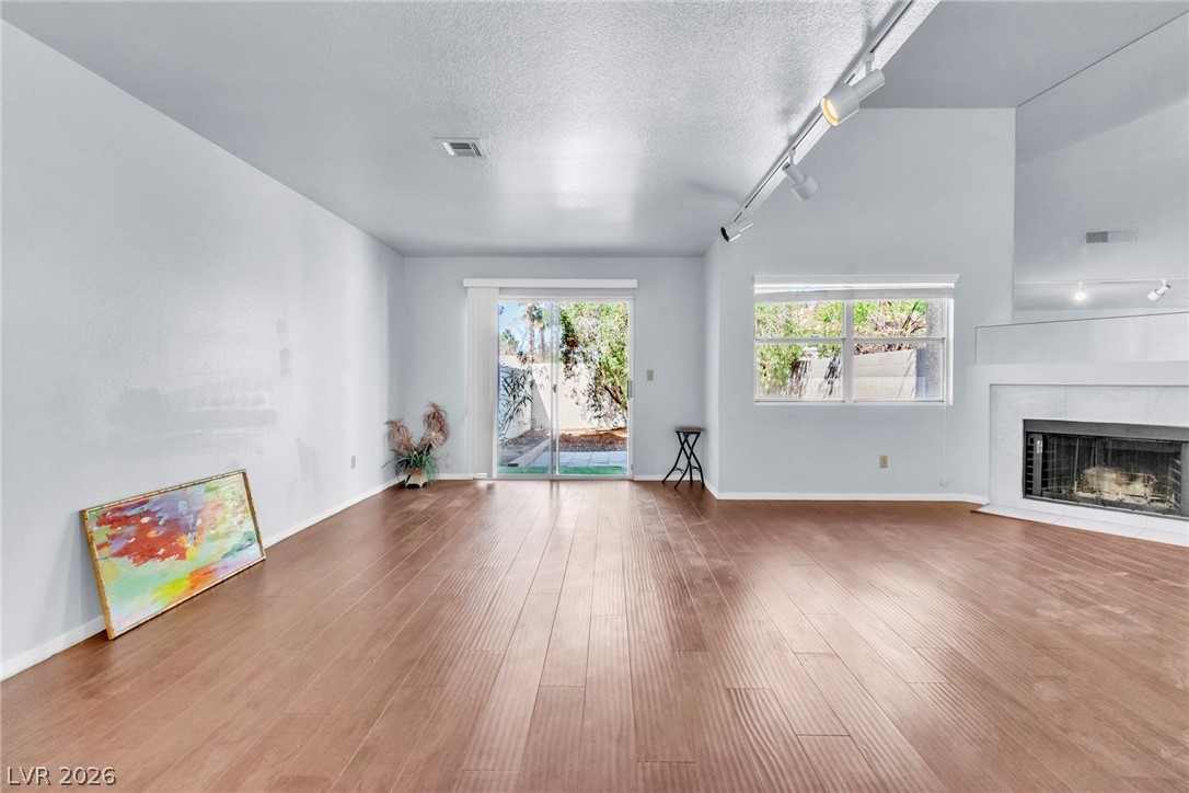 6250 West Flamingo Road, Unit 98 Las Vegas, NV 89103 - Photo 16 of 40 Unfurnished living room featuring a fireplace, wood finished floors, a textured ceiling, rail lighting, and visible vents