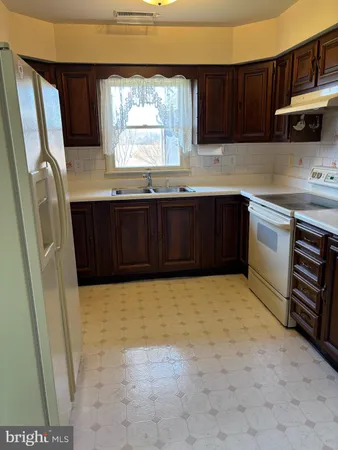 a kitchen with granite countertop a refrigerator a sink a stove a microwave and wooden cabinets