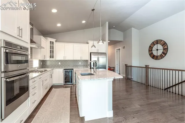 a kitchen with stainless steel appliances kitchen island granite countertop a stove a sink and a refrigerator