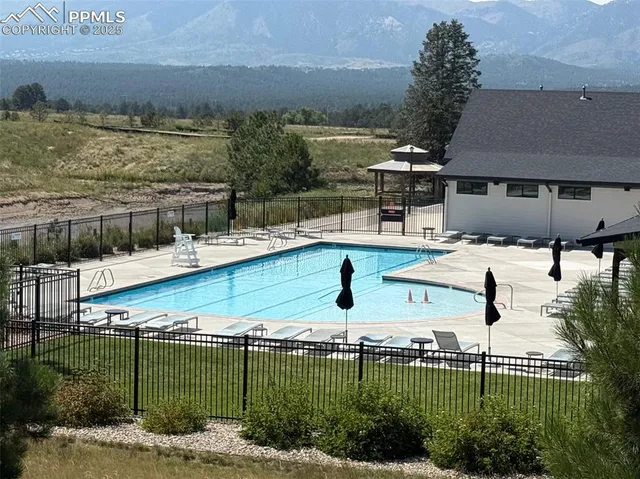 a view of a patio with dining table and chairs under an umbrella with a chandelier
