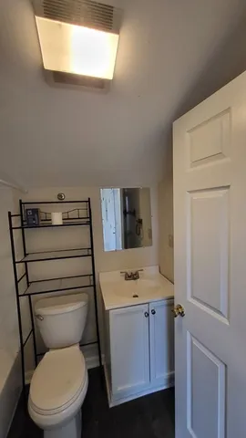 an empty room with wooden floor and a ceiling fan