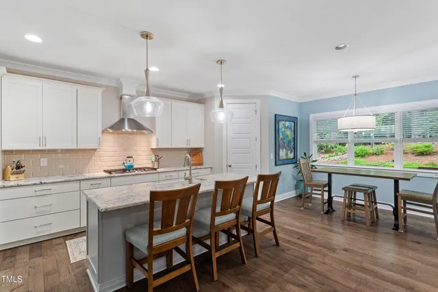 a kitchen with a dining table chairs wooden floor and appliances