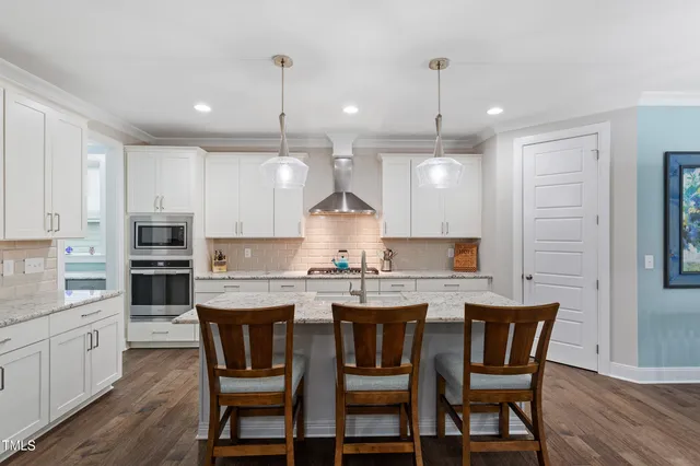 a kitchen with kitchen island a dining table chairs and white cabinets
