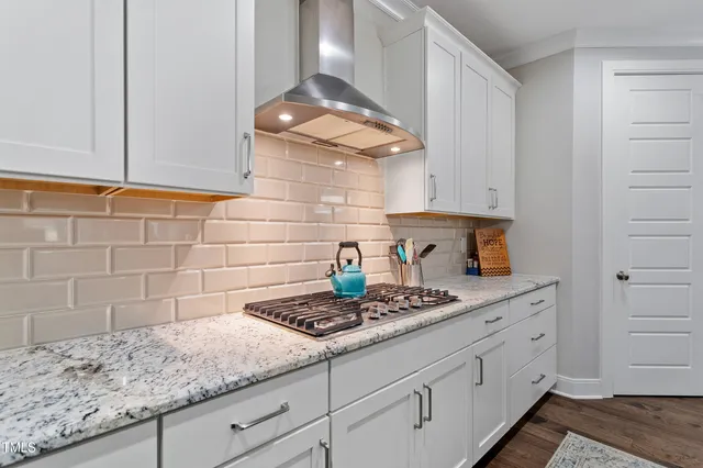 a kitchen with granite countertop white cabinets and a stove
