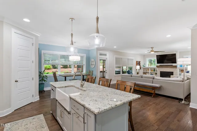 a kitchen with stainless steel appliances granite countertop a sink dishwasher a stove and a dining table with wooden floor