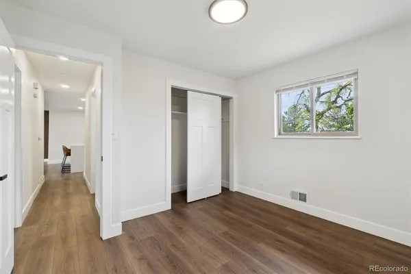 an empty room with wooden floor and bathroom