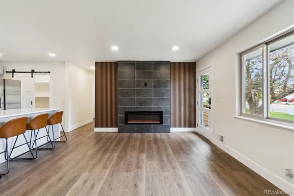 an empty room with wooden floor fireplace and windows