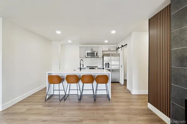 a kitchen with stainless steel appliances a stove a refrigerator a sink dishwasher and a refrigerator with wooden floor