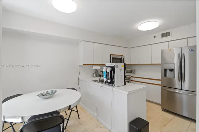 a kitchen with stainless steel appliances a refrigerator a stove a sink and white cabinets