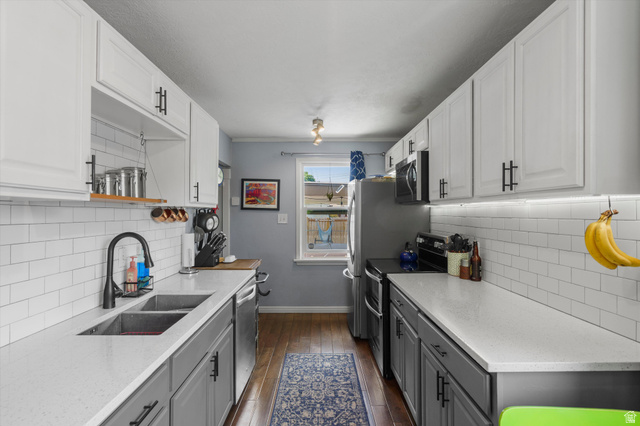 961 33rd Street Ogden, UT 84403 - Photo 11 of 39 Galley kitchen featuring dual-toned cabinetry, subway tile backsplash, stainless steel appliances, and wood-finish flooring