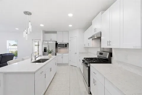 a kitchen with white cabinets sink and stainless steel appliances
