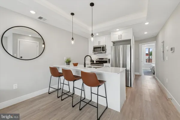 a kitchen with kitchen island a dining table chairs and a wooden floor