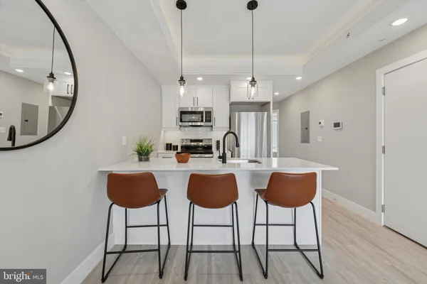 a kitchen with stainless steel appliances granite countertop a stove a refrigerator a oven a sink with a dining table and chairs with wooden floor
