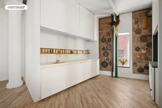 a hallway with white cabinets and wooden floor