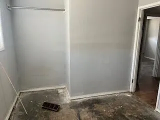 a view of a hallway with wooden floor and a bathroom