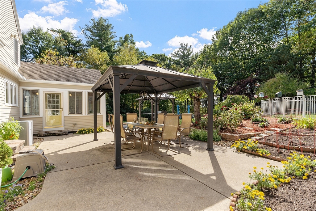 18 Bramley Hill Road Windham, NH 03087 - Photo 9 of 42 a view of a patio with table and chairs under an umbrella with large trees