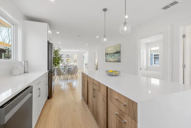 a large kitchen with stainless steel appliances kitchen island a large counter space a sink and living room view