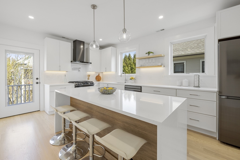 39 Seven Pines Avenue, Unit 39 Cambridge, MA 02140 - Photo 3 of 42 a kitchen with kitchen island a stove a table and chairs in it