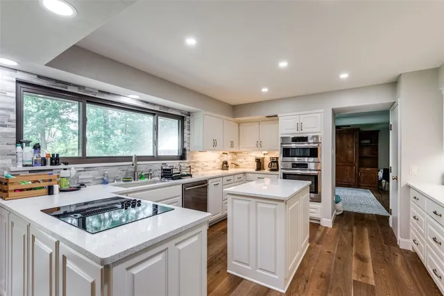 a kitchen with a stove a sink dishwasher and a refrigerator with wooden floor