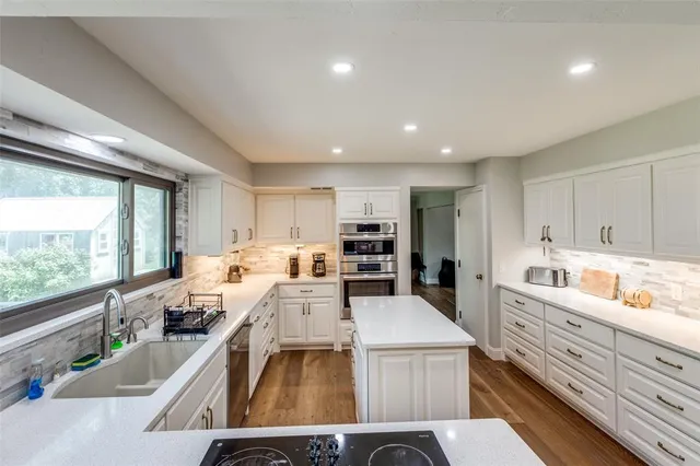 a kitchen that has a lot of cabinets a sink and appliances in it