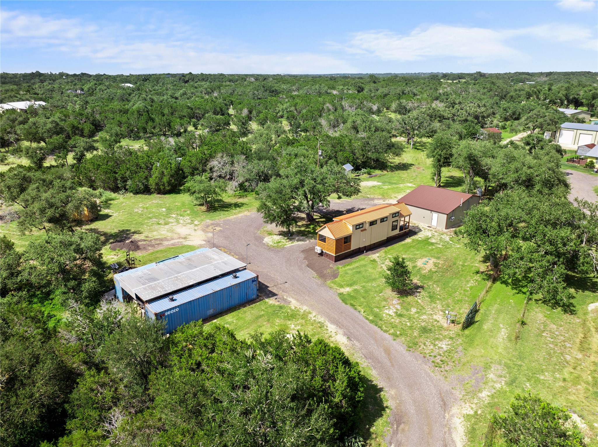 8200 Ranch Road 12 San Marcos, TX 78666 - Photo 5 of 40 Discover a tranquil rural setting with a modern tiny home and practical outbuildings amidst verdant trees.