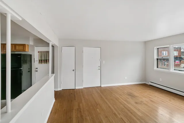 a view of an empty room with window and wooden floor
