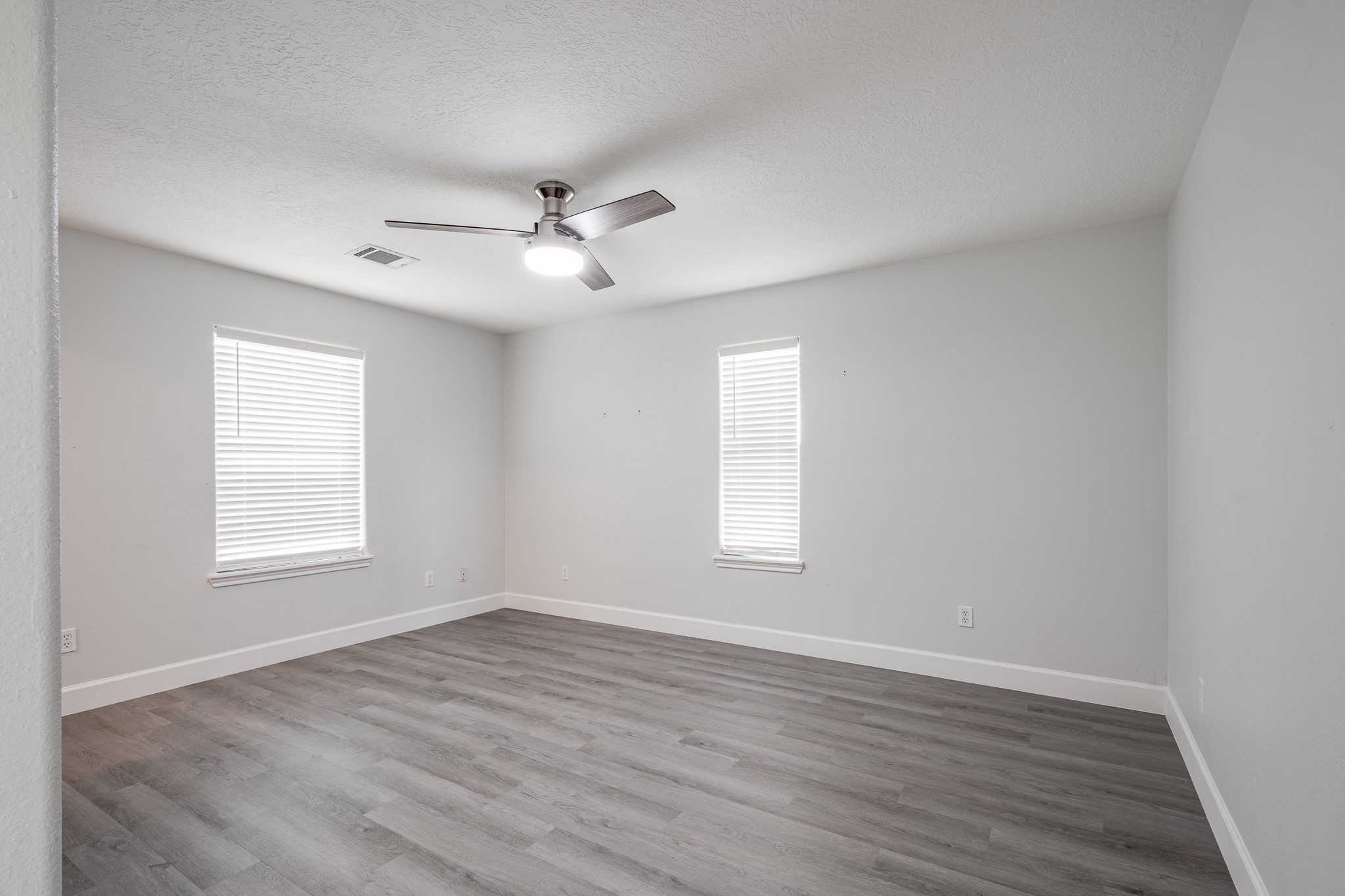 9026 McGallion Road Houston, TX 77022 - Photo 16 of 34 an empty room with wooden floor ceiling fan and windows