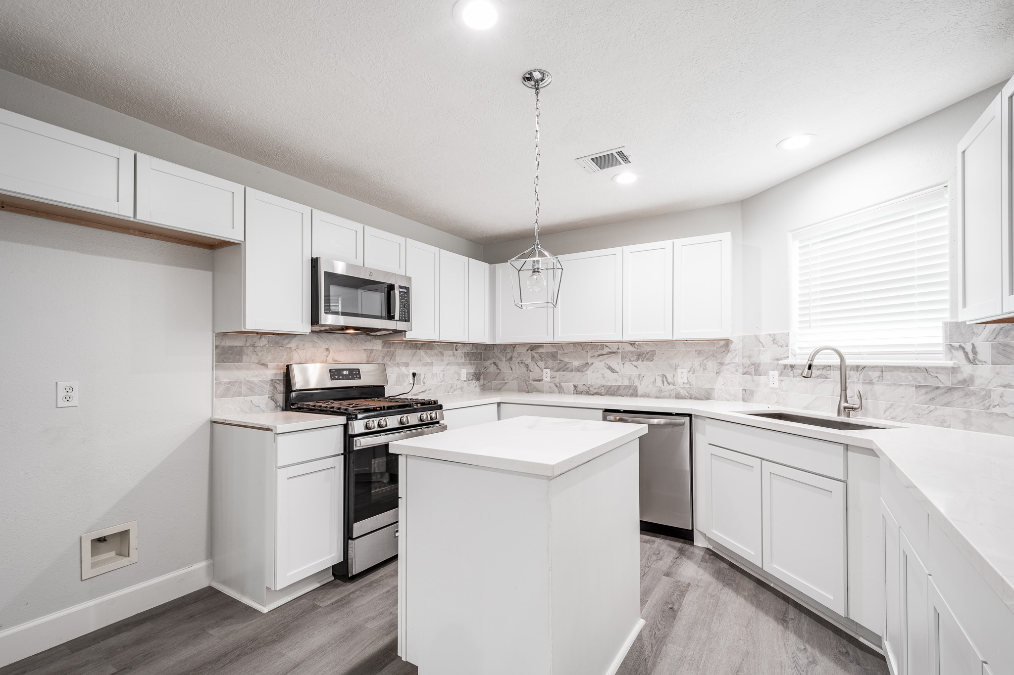 9026 McGallion Road Houston, TX 77022 - Photo 10 of 34 a kitchen with a sink a stove a microwave and cabinets