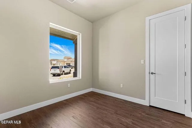 a view of an empty room with wooden floor and closet