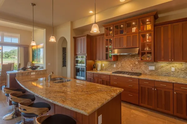 a kitchen with kitchen island granite countertop a sink a counter top space and living room view