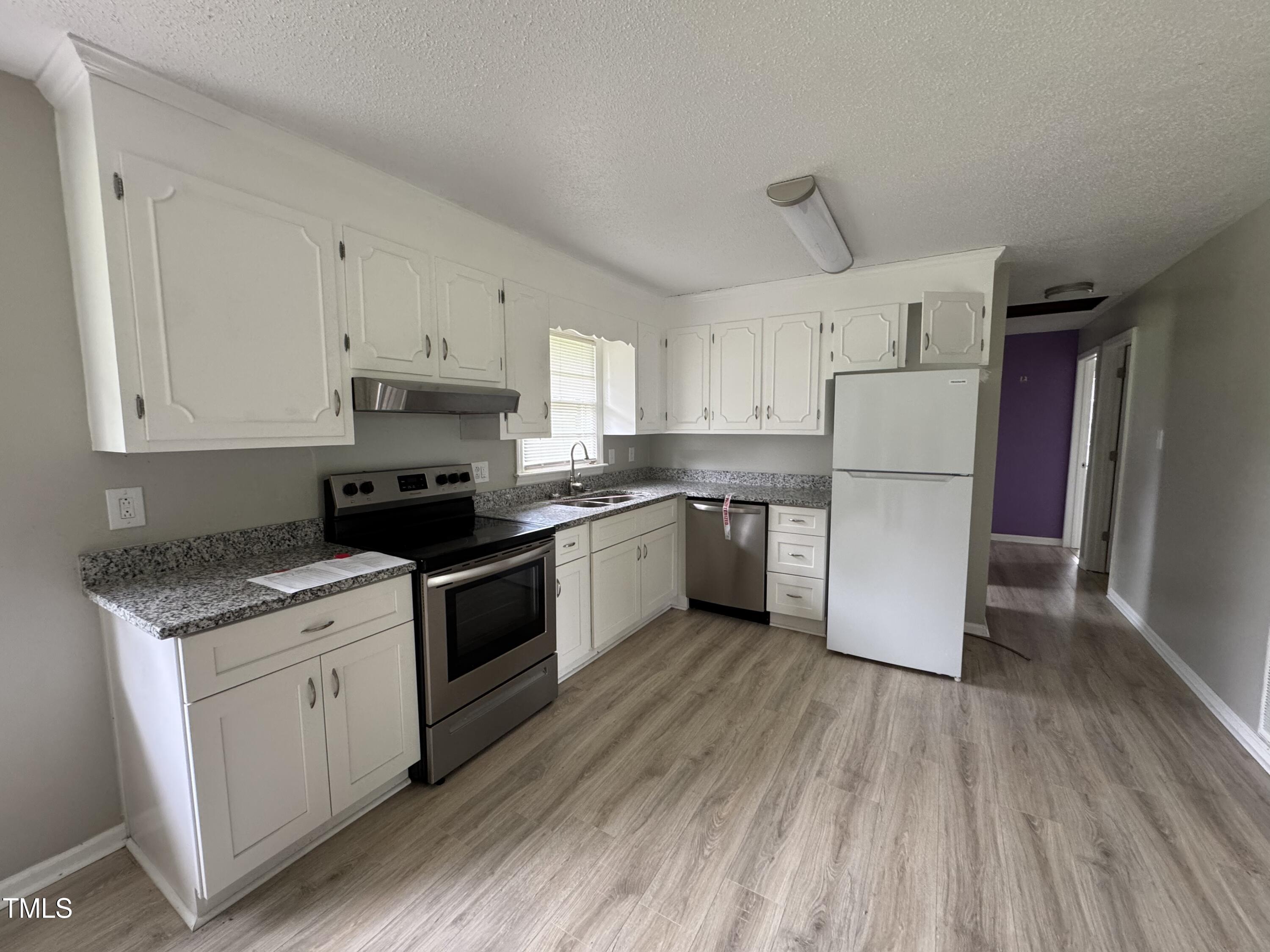 1064 Abbott Road Henderson, NC 27537 - Photo 4 of 9 a kitchen with a refrigerator a stove top oven a sink dishwasher and a refrigerator with wooden floor