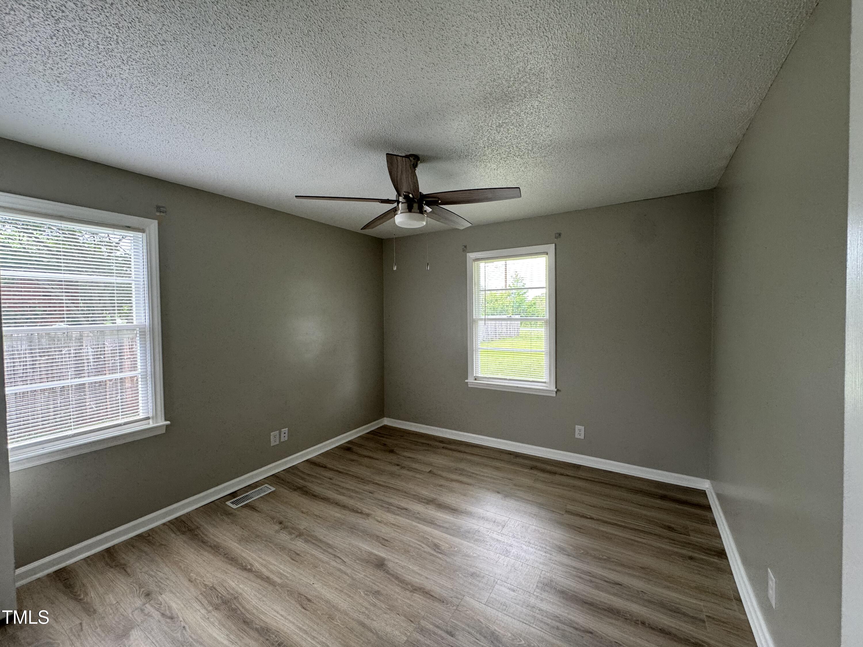 1064 Abbott Road Henderson, NC 27537 - Photo 6 of 9 a view of an empty room with wooden floor and a window