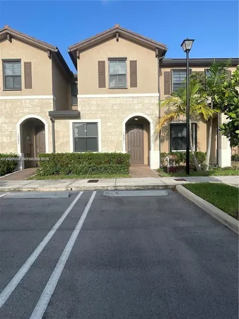 a front view of a house with yard and parking