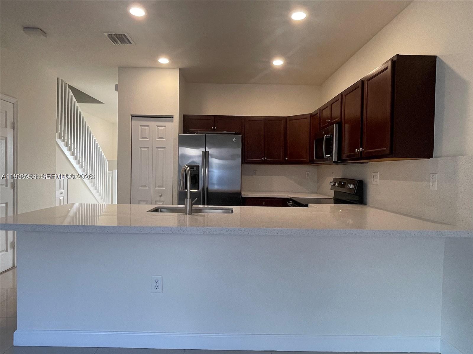 10491 West 34th Court Hialeah, FL 33018 - Photo 9 of 37 a kitchen with stainless steel appliances granite countertop a refrigerator a stove and a sink with wooden cabinets