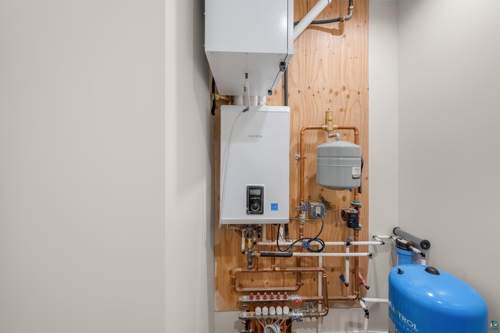 1241 Airport Road Two Harbors, MN 55616 - Photo 46 of 54 Tankless water heater with copper piping, expansion tank, and water treatment system mounted on a wood-paneled wall