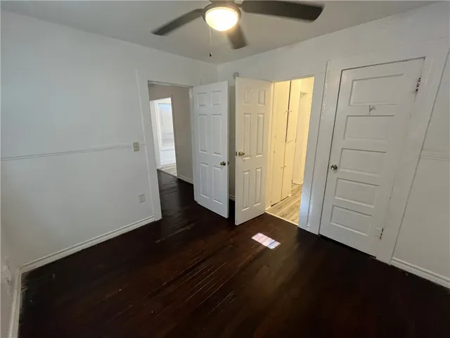 an empty room with wooden floor cabinet and windows