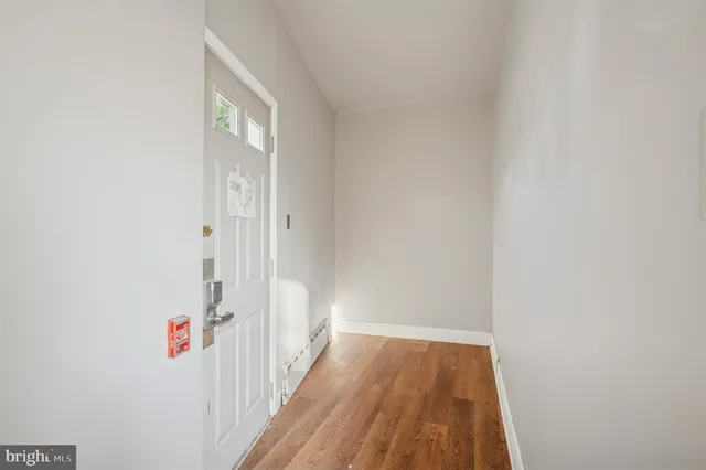 a view of a hallway with wooden floor and a bathroom