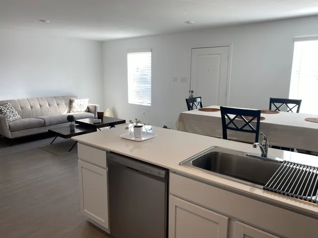 a kitchen with a sink and couches with a fireplace